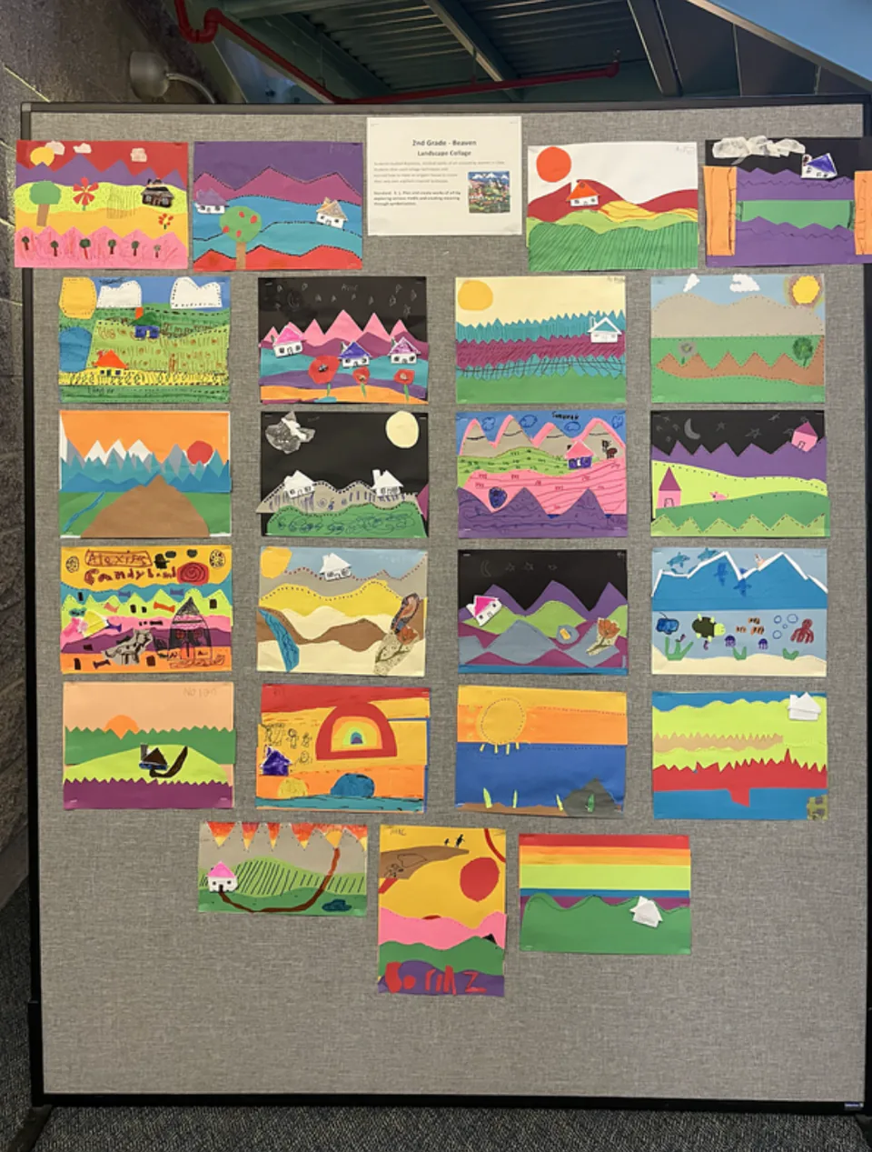 A classroom display board filled with rows of children’s paper landscape collages.