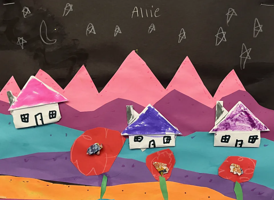 A paper collage landscape of pink and purple mountains dotted with small houses and red flowers.