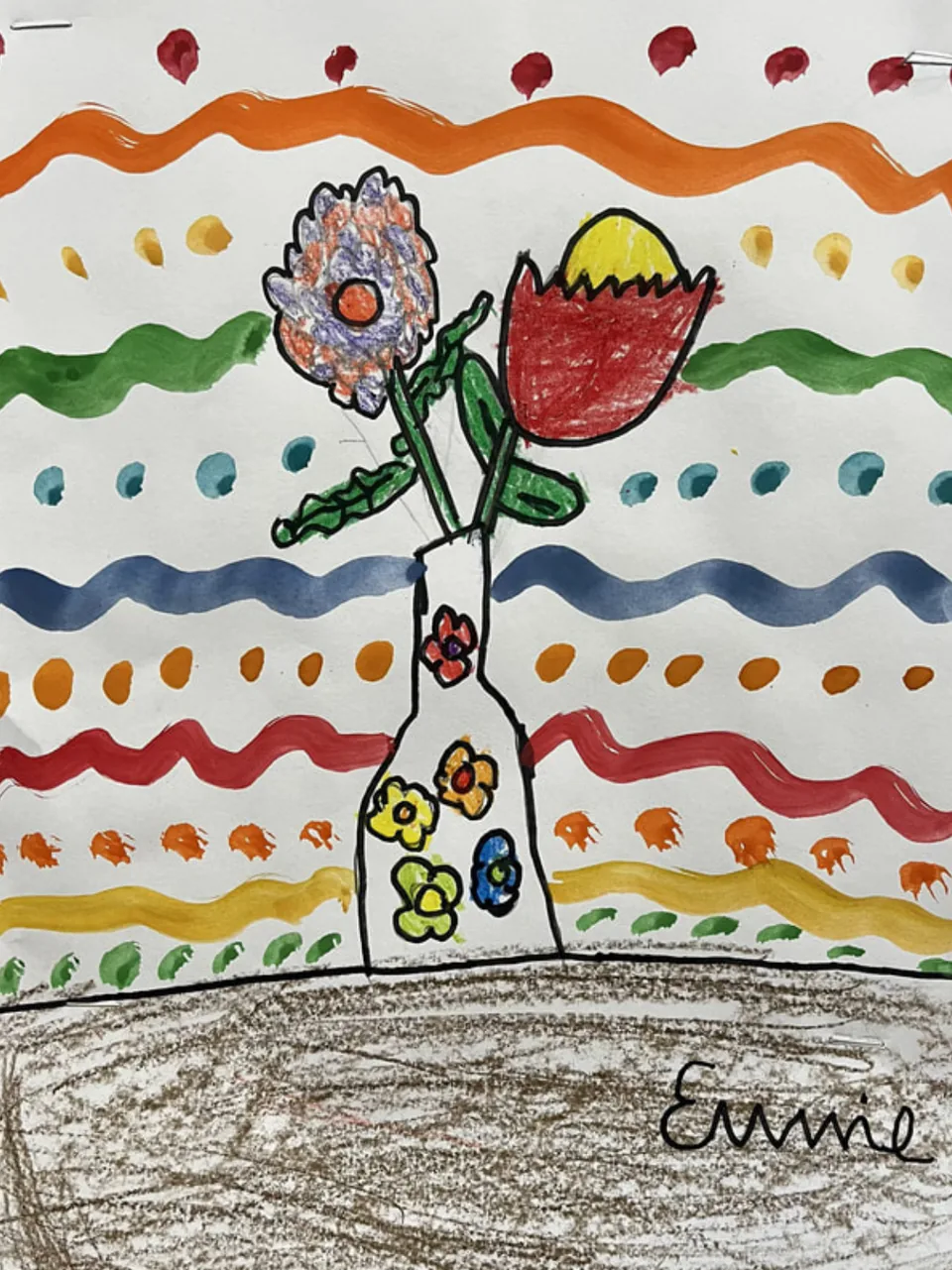 A child’s still life of a single flower in a patterned vase, drawn in crayon over bands of painted colour.