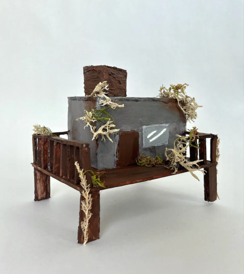A foam core architectural model of an open structure with a dark screen set into one side.